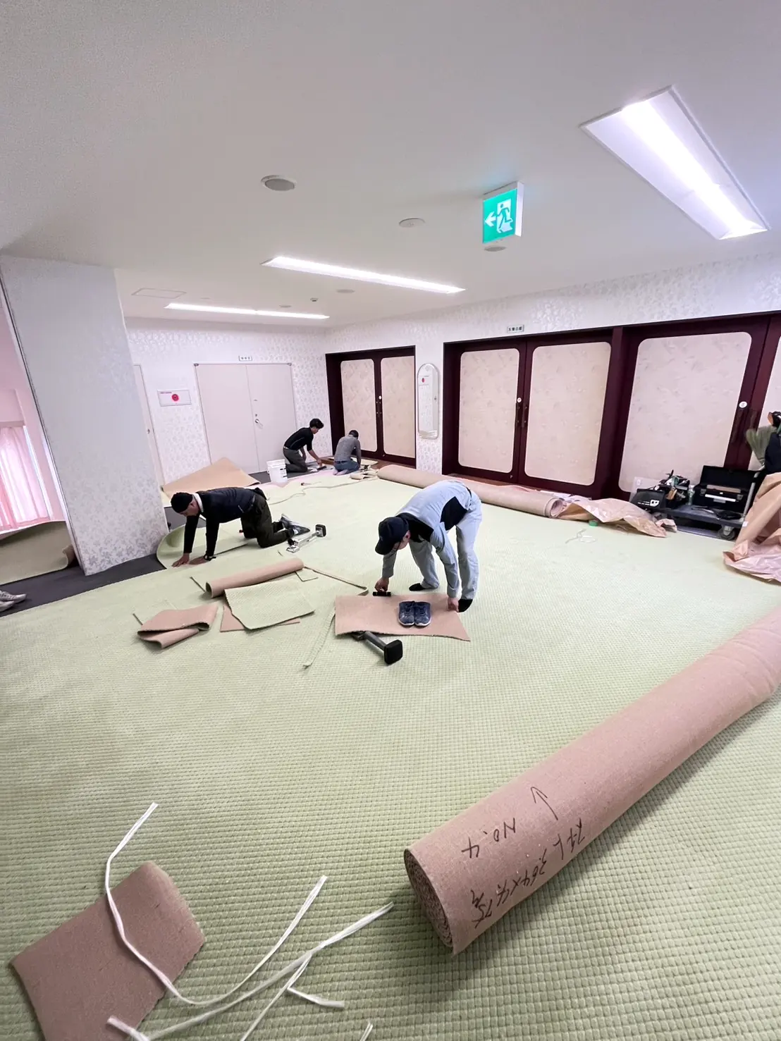 数人の職人がカーペットを広げて貼り込んでいるところ