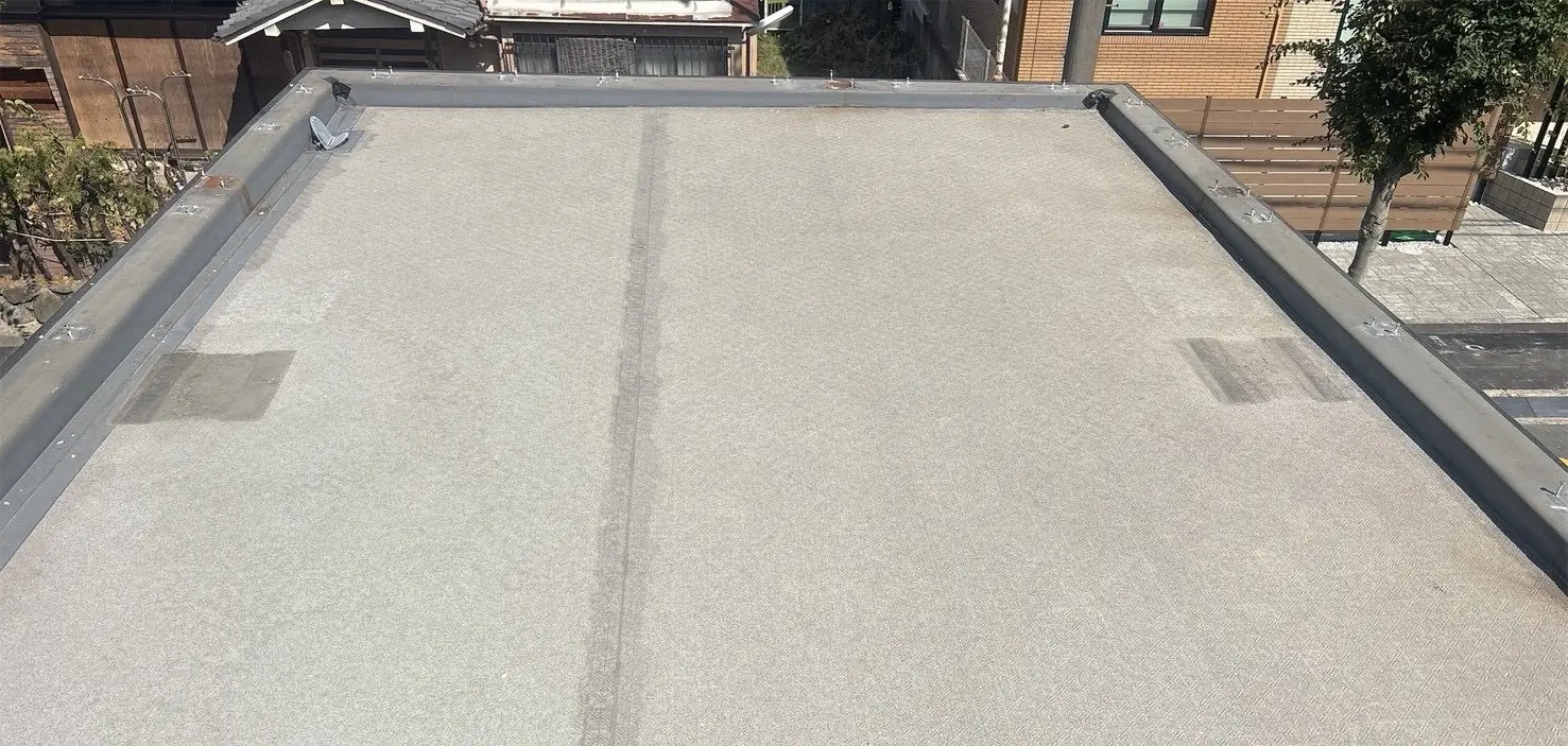 防水工事が終わった屋上。グレーの防水層が一面に敷かれ、まわりの立ち上がりと笠木まで仕上がっている
